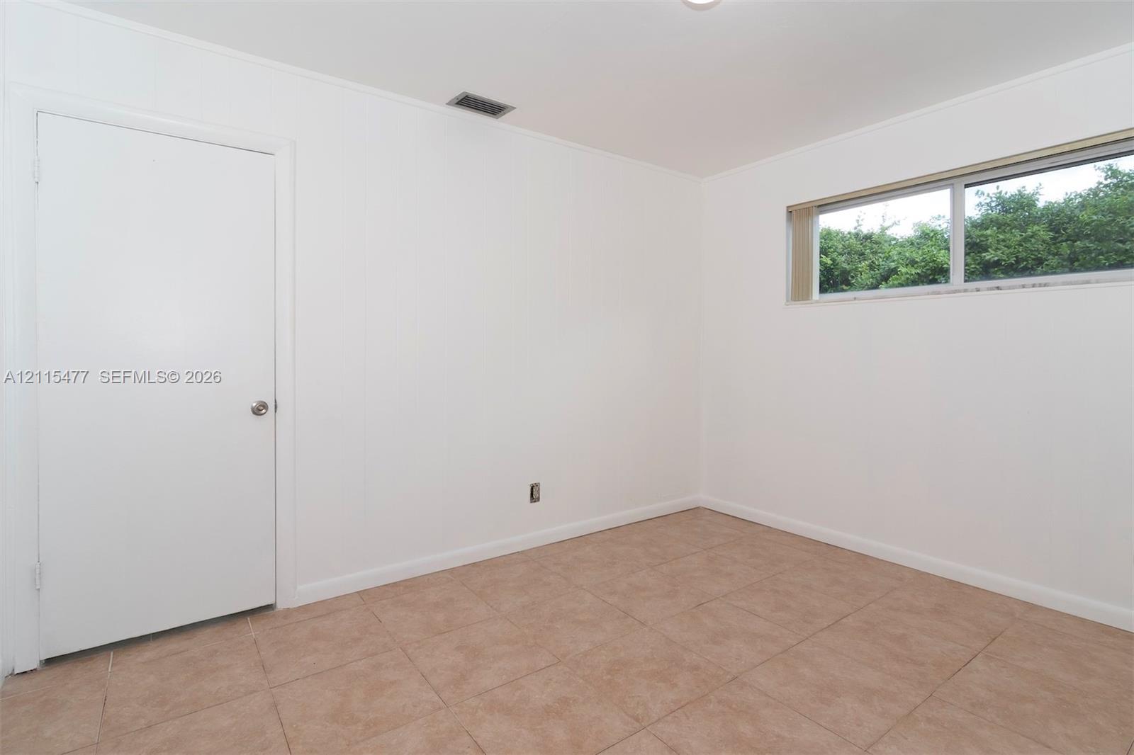 Interior room featuring neutral wall finishes, tile flooring, and a single-pane sliding window