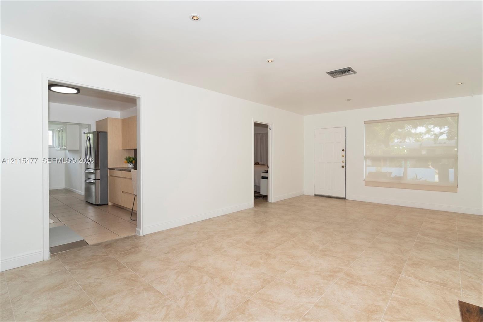 Neutral-toned tile flooring, recessed ceiling lighting, and large window with integrated shade