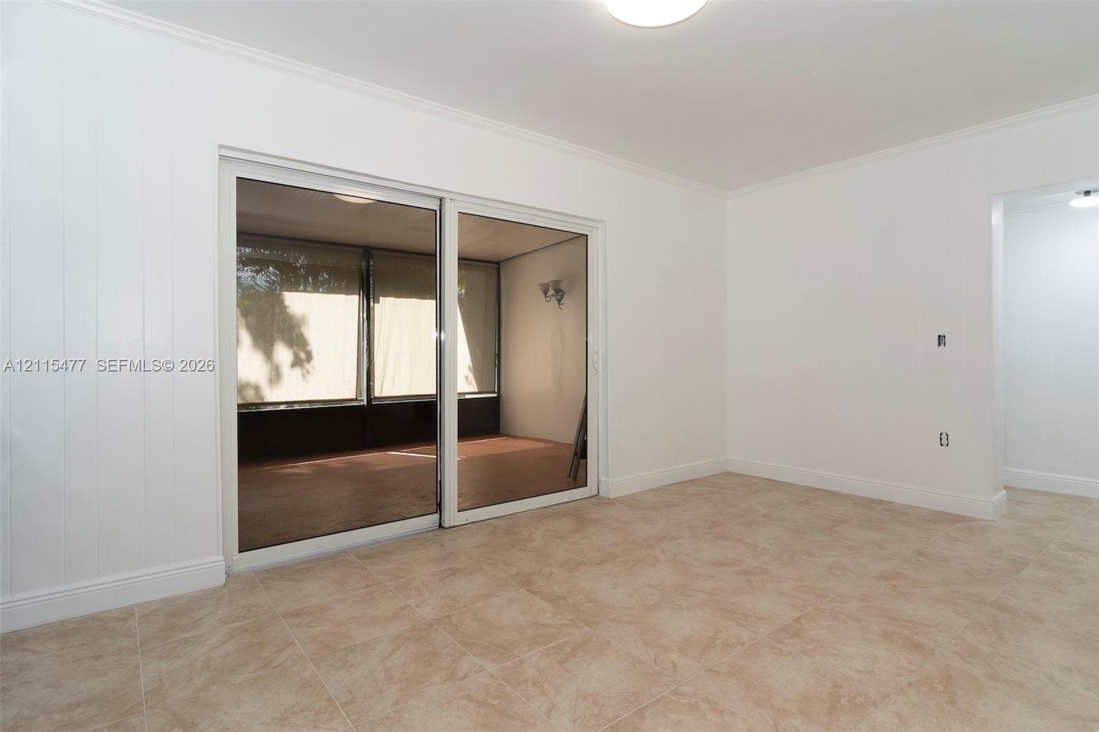 Interior space featuring large-format ceramic tile flooring, vertical paneling, and a dual-panel sliding glass door
