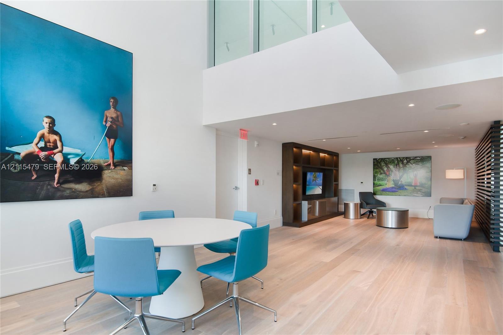 Double-height ceilings, light-toned wood-finish flooring, recessed lighting, and custom dark-toned built-in cabinetry featuring integrated shelving