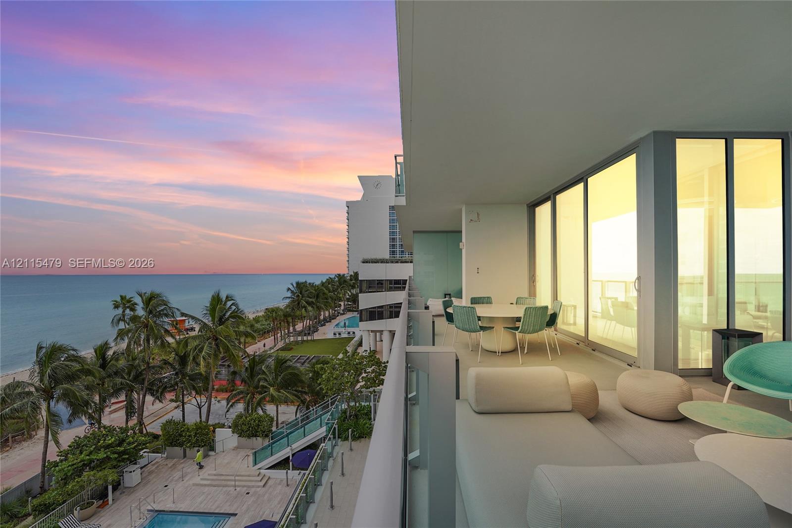 Expansive covered terrace featuring glass panel railings, floor-to-ceiling sliding glass doors, and panoramic ocean and coastline scenery Expansive covered terrace featuring glass panel railings, floor-to-ceiling sliding glass doors, and panoramic ocean and coastline scenery