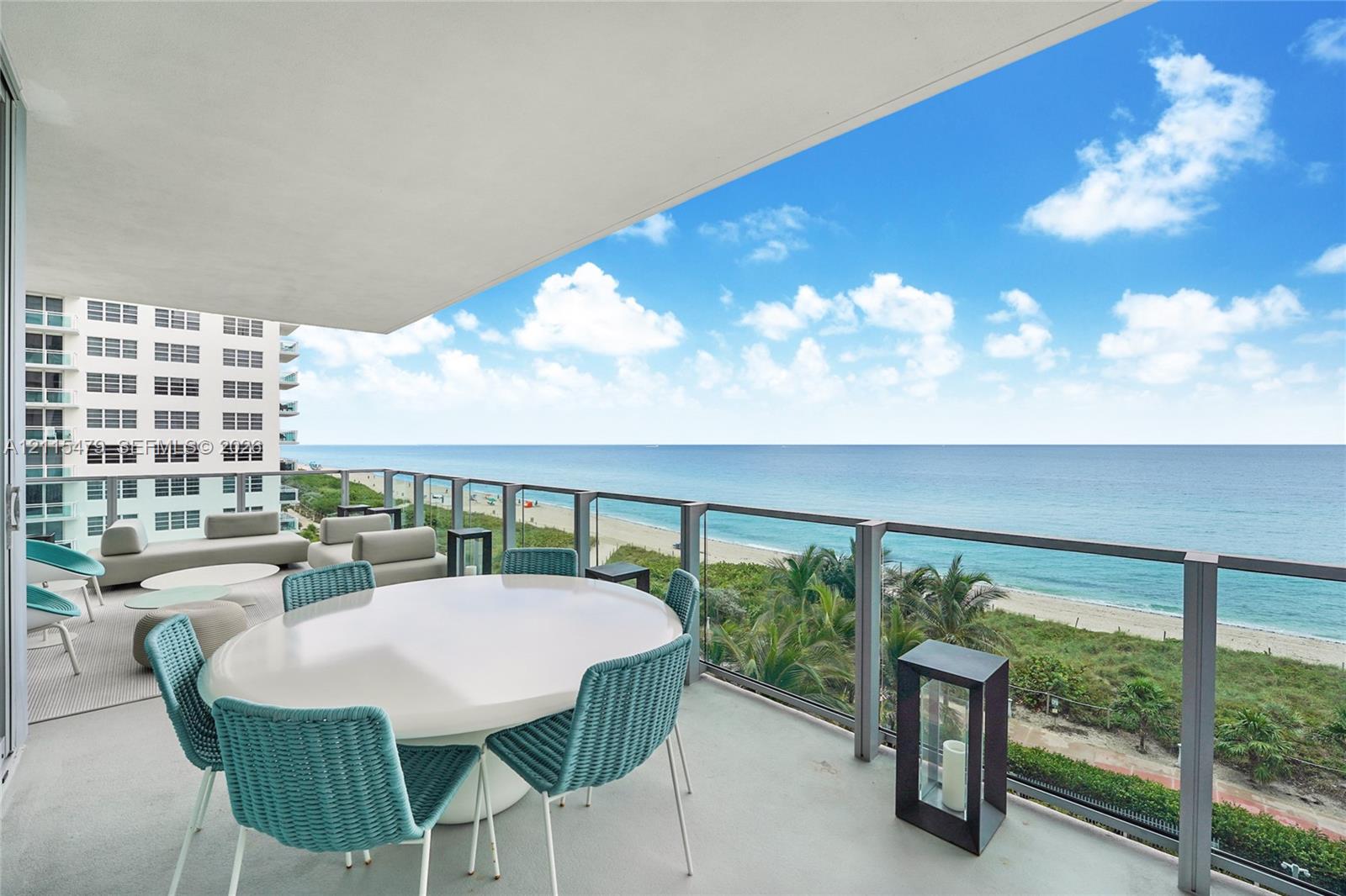 Covered balcony featuring a glass and metal railing, concrete flooring, and an expansive ocean backdrop