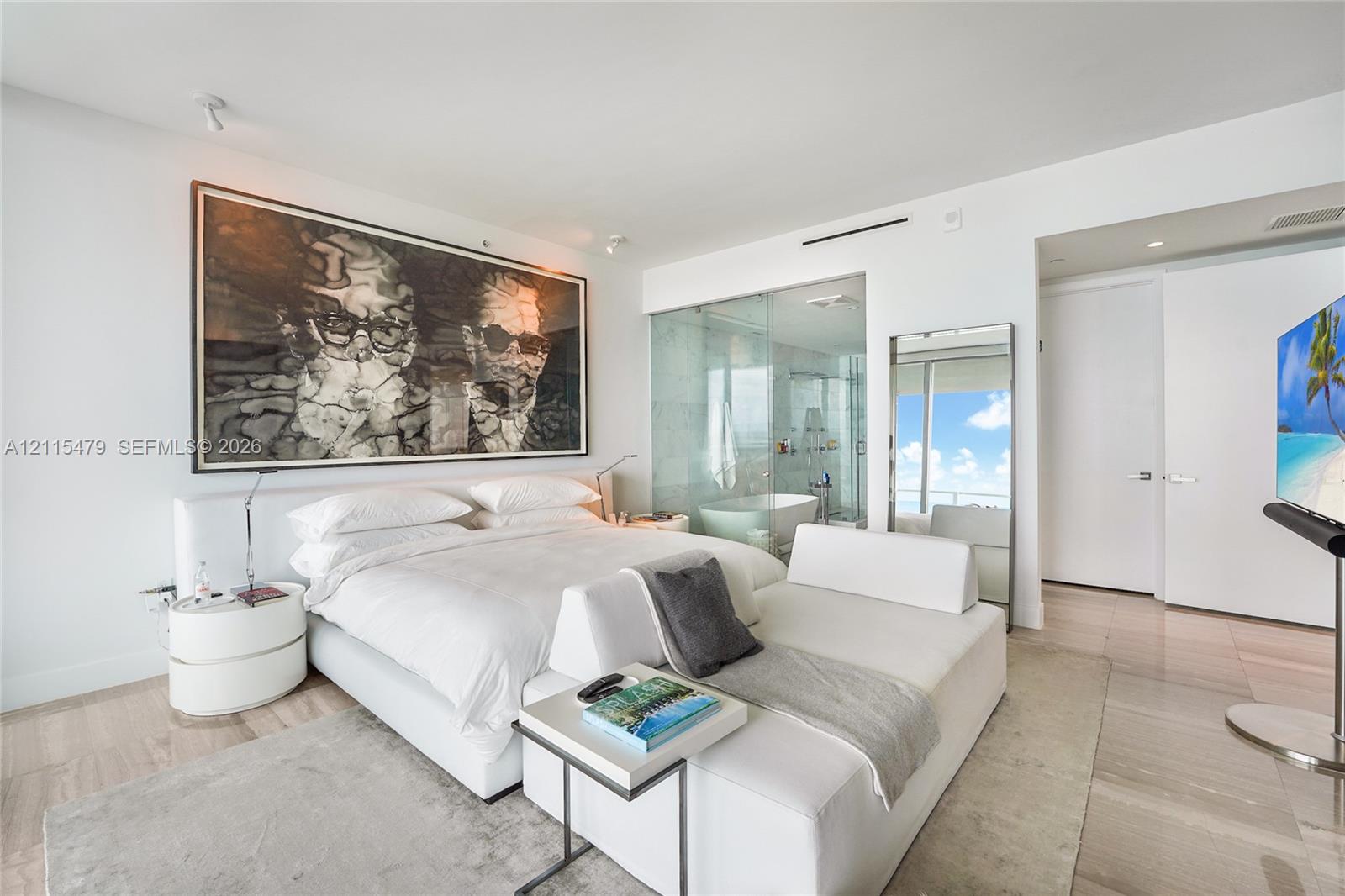 Light-toned large-format tile flooring, glass-enclosed shower, freestanding soaking tub, and smooth-finish white ceiling with recessed lighting