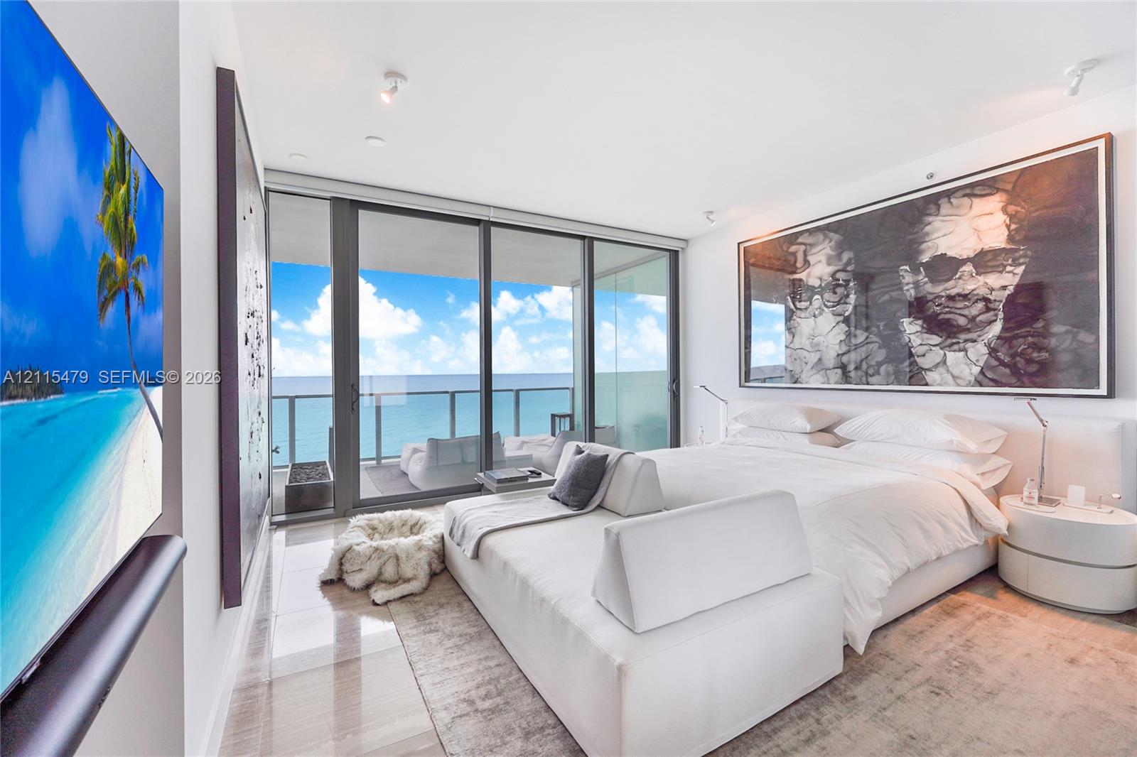 Floor-to-ceiling glass sliding doors opening to an exterior balcony, polished stone flooring, recessed ceiling lighting, and a neutral color palette
