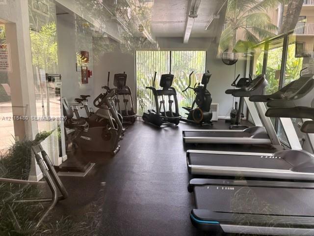 Fitness center featuring rubberized flooring, expansive floor-to-ceiling windows, and natural lighting