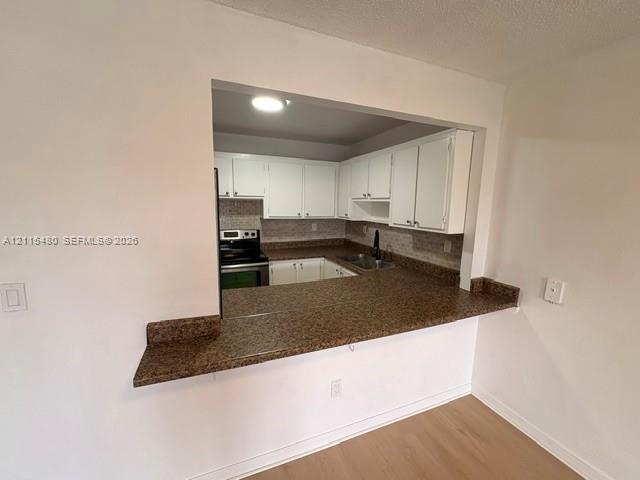 Kitchen pass-through featuring an expansive stone-finish countertop, white cabinetry, integrated stainless steel appliances, and a double-basin sink