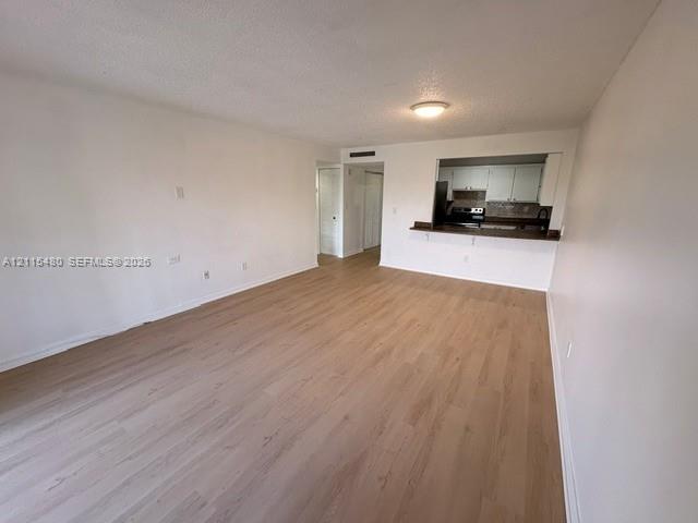Open-concept area featuring wood-finish flooring, a pass-through opening, and a built-in breakfast bar