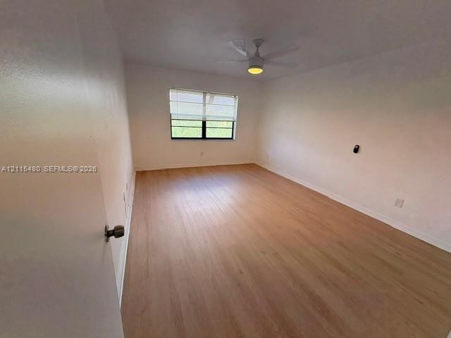 Room featuring wood-finish flooring, a multi-pane window with white blinds, and a ceiling-mounted fan with integrated lighting