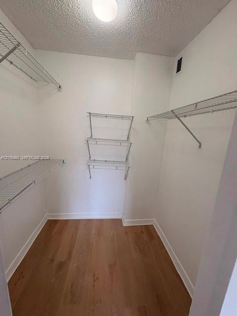Walk-in storage space featuring wood-finish flooring and tiered metal shelving
