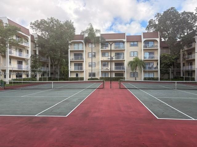 Dual tennis courts with red and green surfacing, enclosed by perimeter fencing