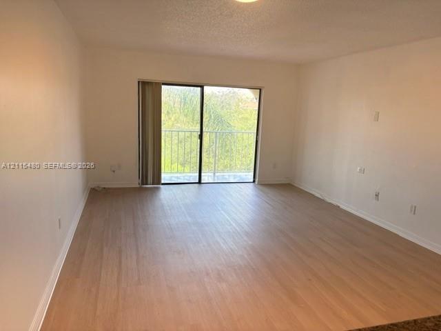Neutral interior featuring wood-finish flooring, sliding glass door, and metal balcony railing