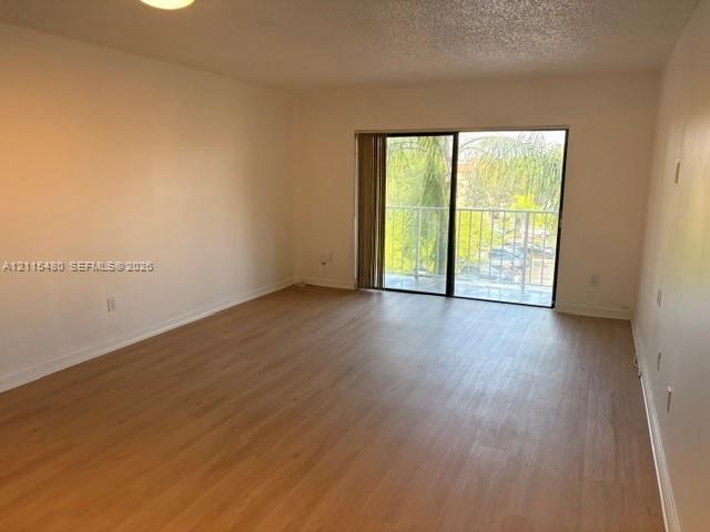 Living area featuring wood-finish flooring, ceiling lighting, and sliding glass doors with access to an exterior balcony