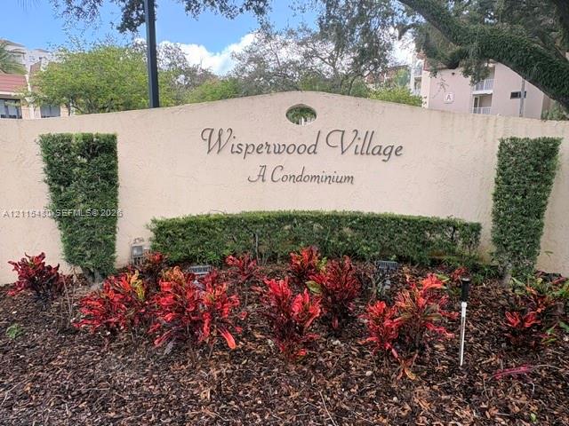 Stucco community monument sign featuring manicured topiary shrubs and decorative landscaping