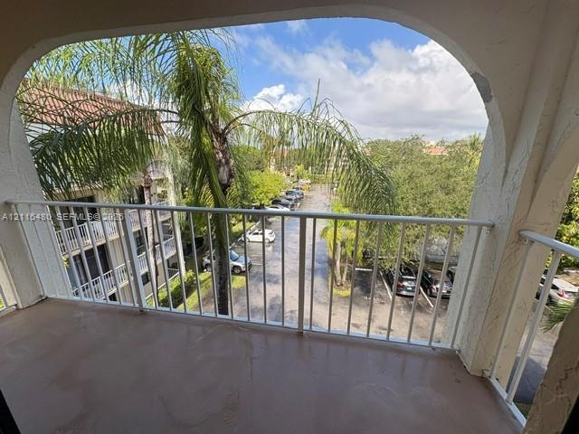 Covered balcony featuring an arched entryway, smooth-finish concrete flooring, and a white metal railing