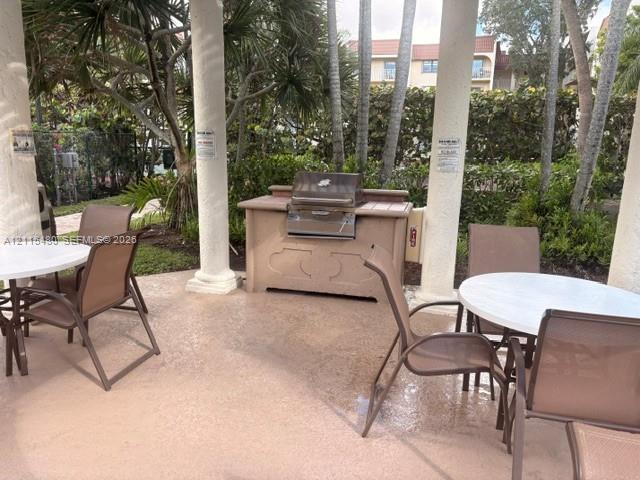 Covered outdoor pavilion featuring structural columns and a built-in stainless steel grill