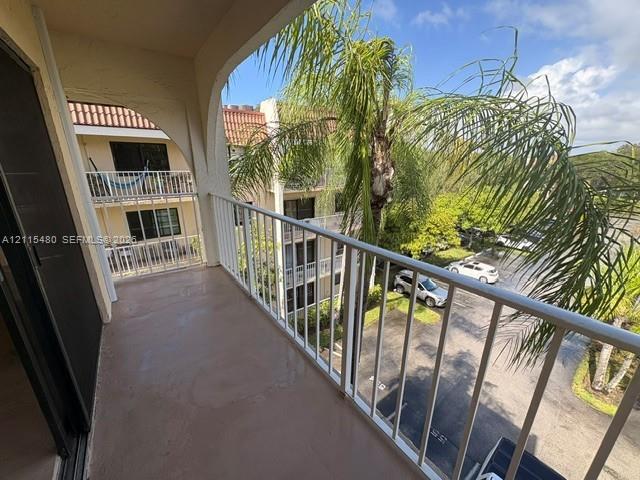Covered balcony with a concrete floor, arched architectural detailing, and white metal railing