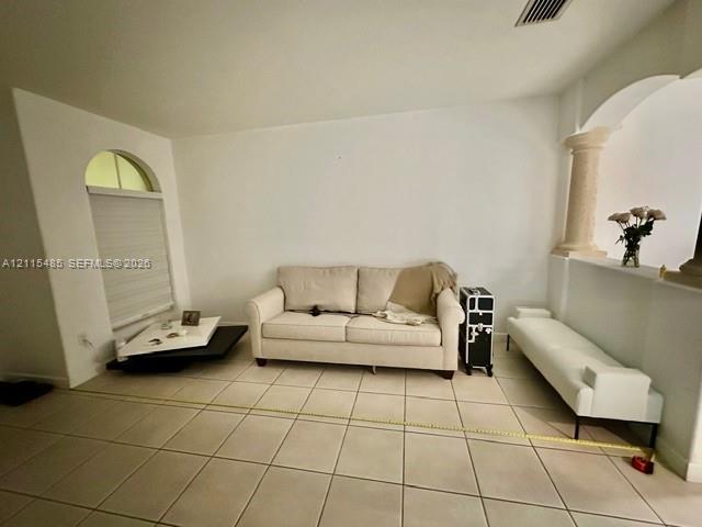Ceramic tile flooring, arched window with semi-circular transom, and decorative column featuring a stone-finish pedestal