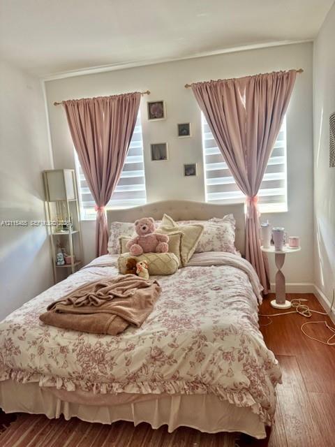Wood-finish flooring, dual windows with banded roller shades, and gold-finish curtain hardware