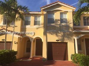 Mediterranean-style exterior featuring a tile roof, arched entryway, balcony with decorative metal railing, and attached garage Mediterranean-style exterior featuring a tile roof, arched entryway, balcony with decorative metal railing, and attached garage