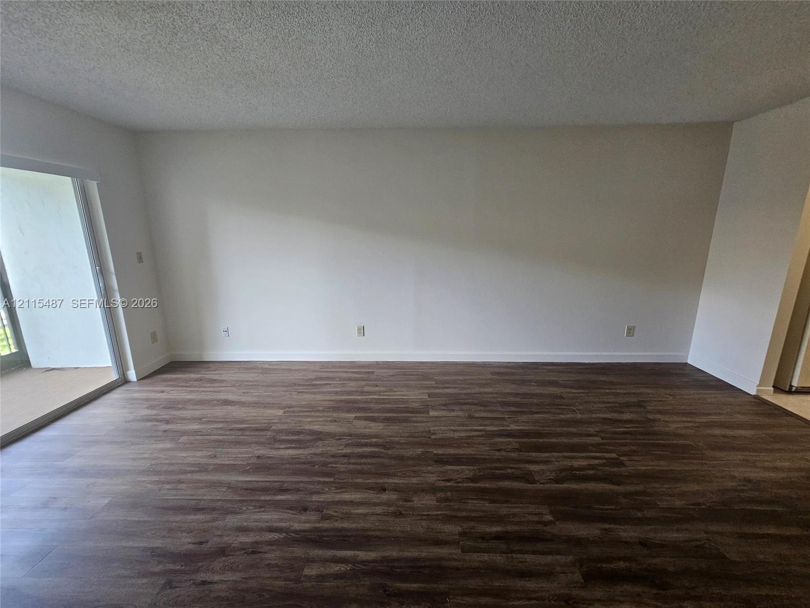Interior space featuring wood-finish flooring, a sliding glass door, and a textured ceiling