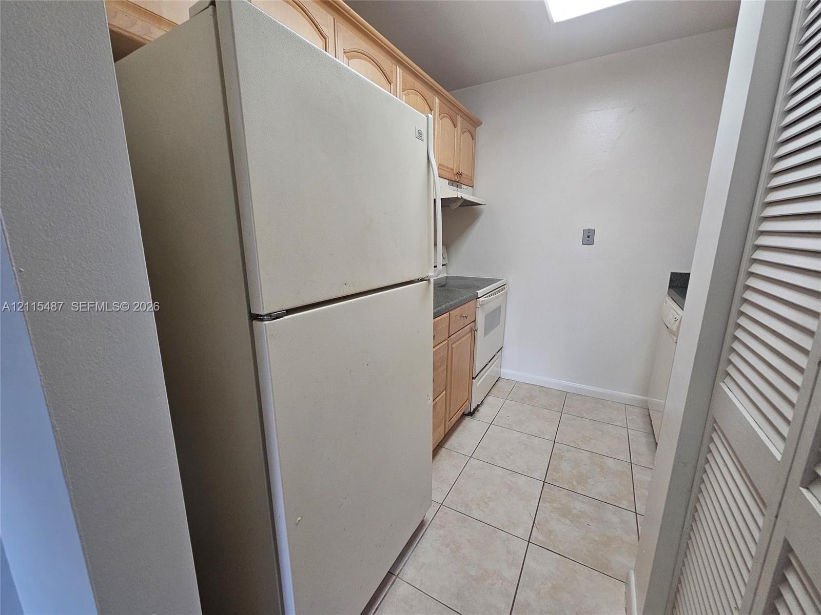 Kitchen featuring light wood cabinetry, tile flooring, and built-in appliances
