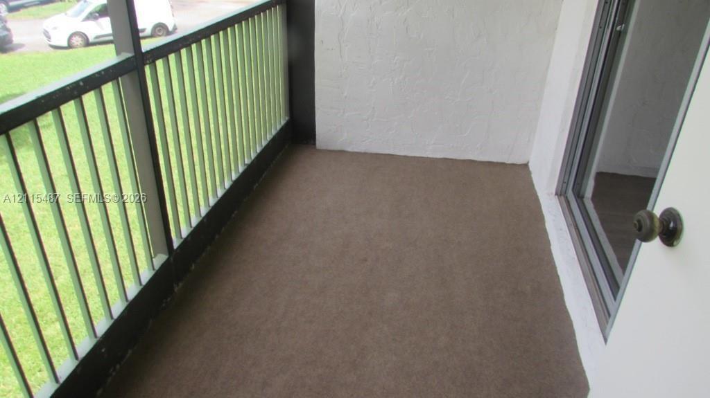 Covered balcony featuring textured walls, painted metal railing, and concrete flooring