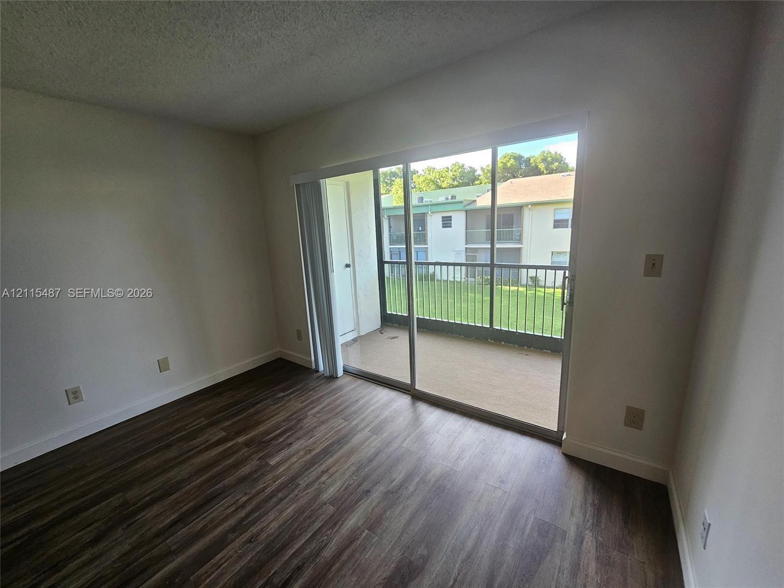 Sliding glass door opening to a private balcony with metal railing and wood-finish flooring