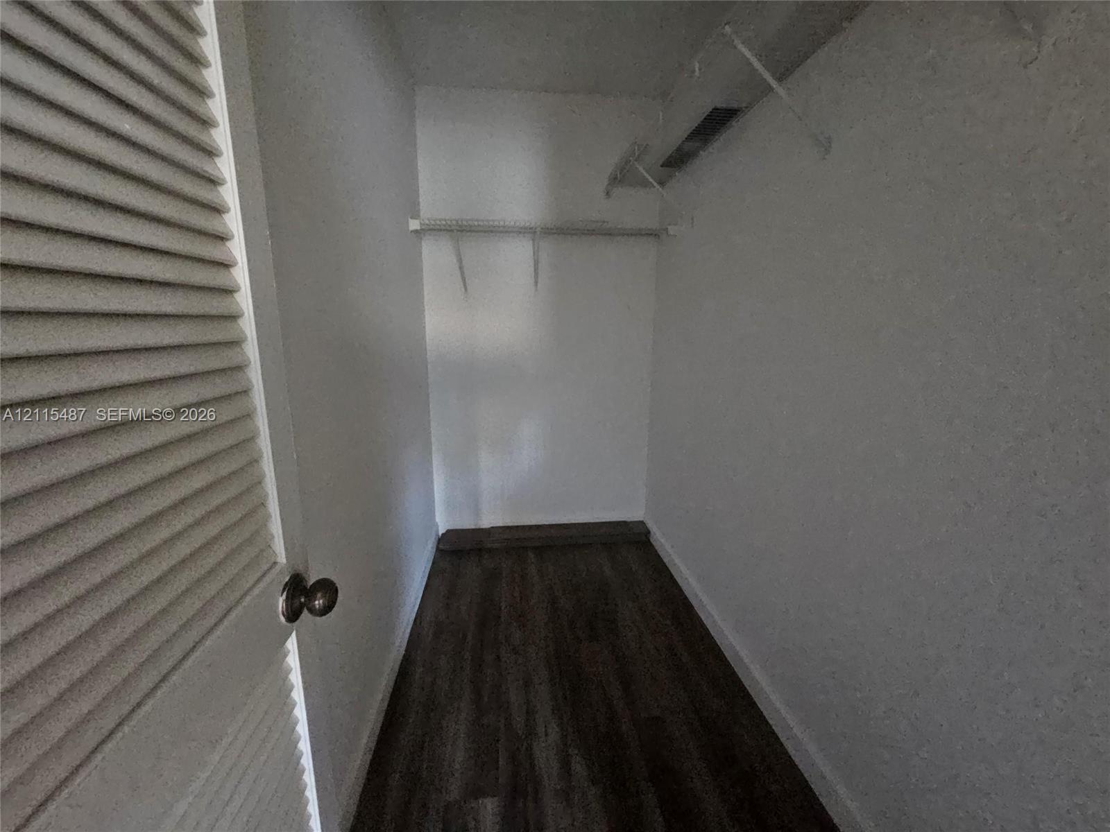 Walk-in closet featuring wood-finish flooring, white walls, and built-in white wire shelving