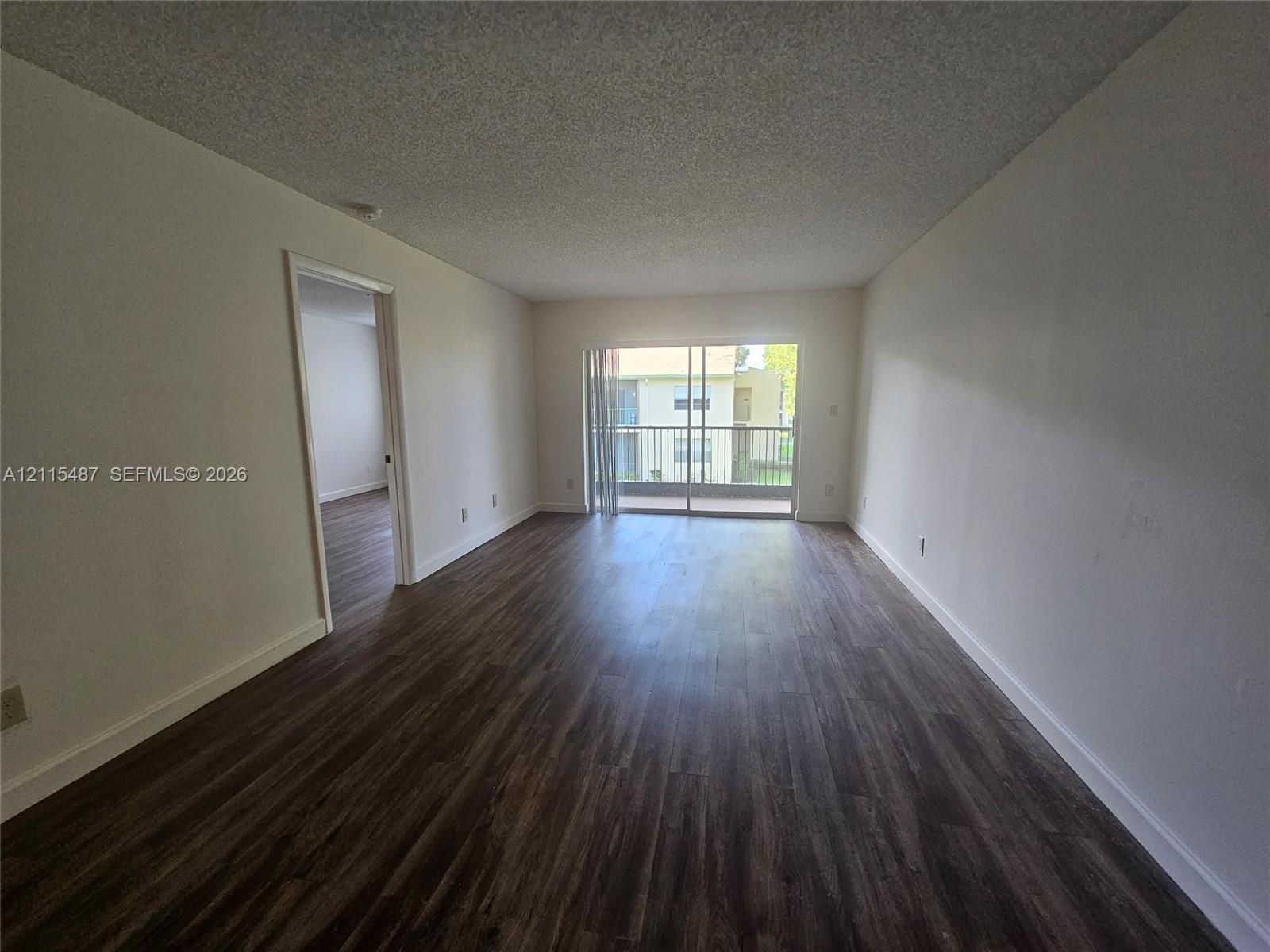 Open floor plan featuring wood-finish flooring, sliding glass doors, and a private balcony