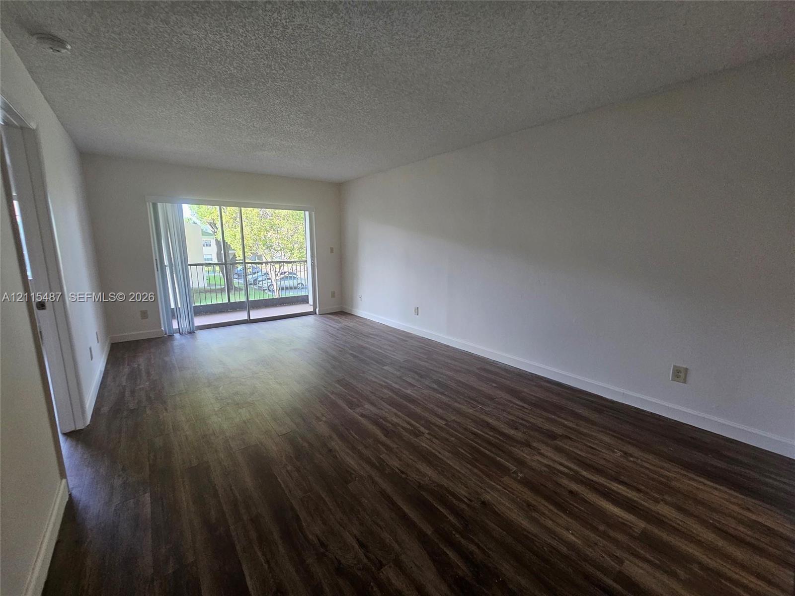 Open living area featuring wood-finish flooring, neutral wall paint, and a sliding glass door providing external access