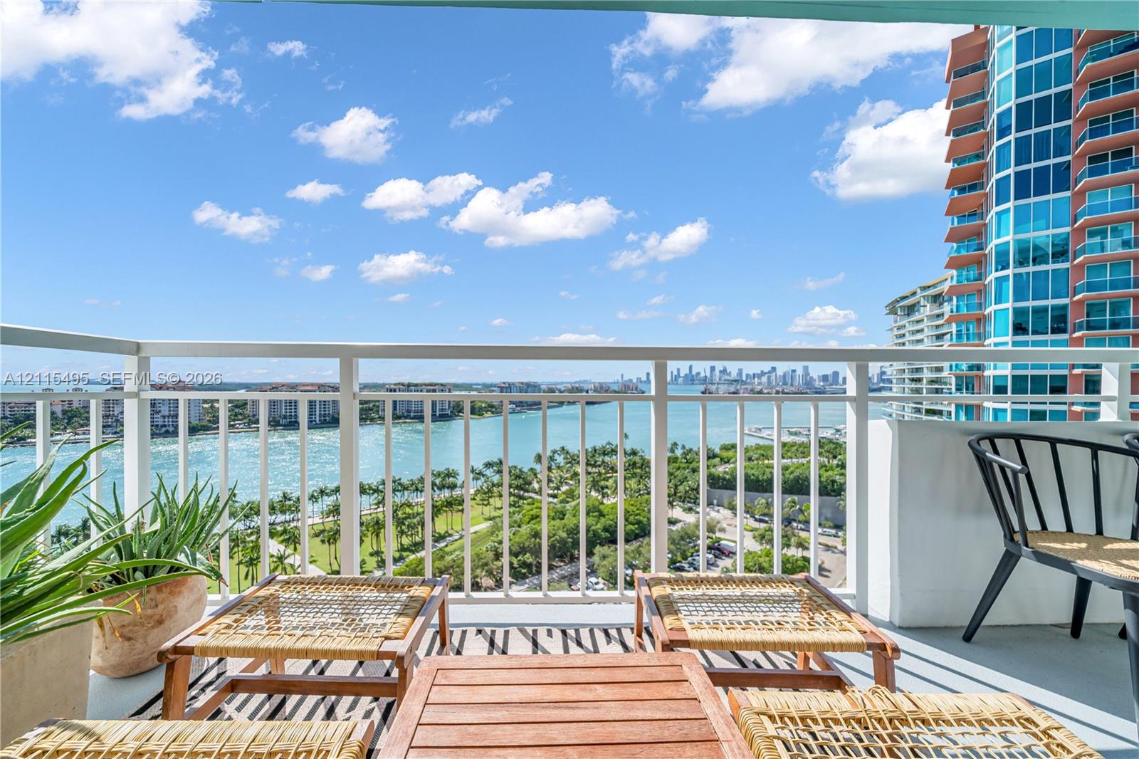 Private balcony featuring white metal railing and open-air access to coastal and urban skyline scenery