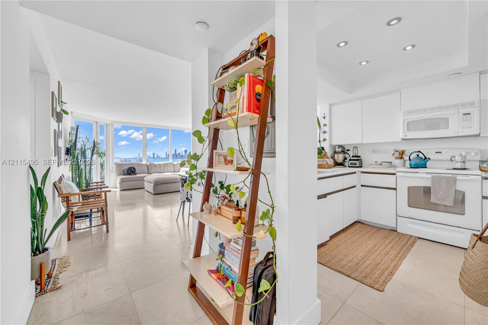 Open-concept living space featuring large-format tile flooring, white cabinetry, integrated recessed lighting, and expansive floor-to-ceiling windows