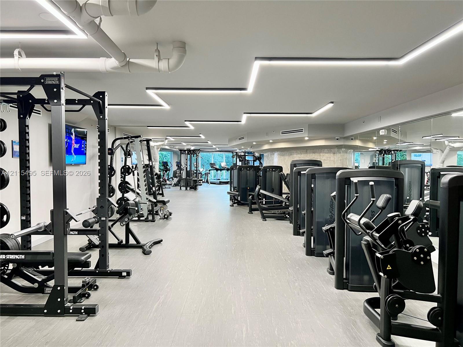 Fitness center featuring linear recessed ceiling lighting, full-wall mirrors, and resilient flooring