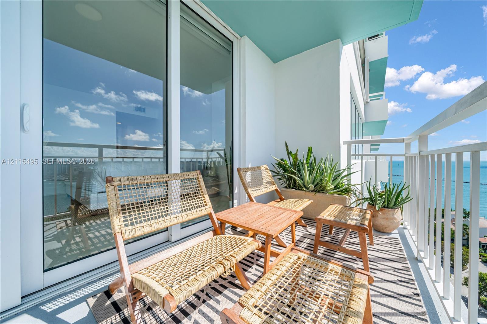 Private balcony featuring a white metal railing, floor-to-ceiling glass sliding door, and a vibrant teal-painted ceiling