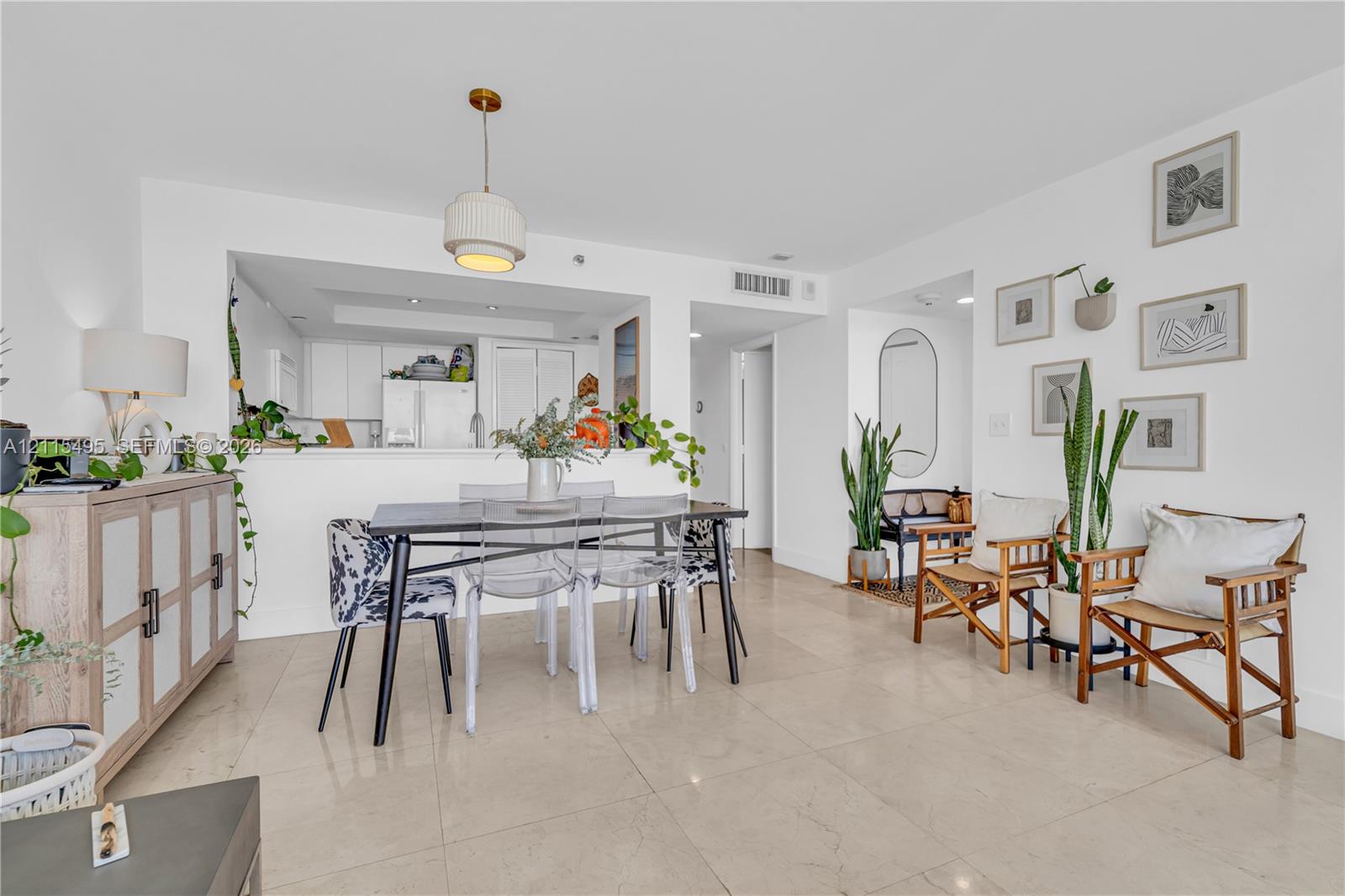Open-concept dining area featuring large-format tile flooring, a pass-through kitchen opening, and a contemporary pendant light fixture