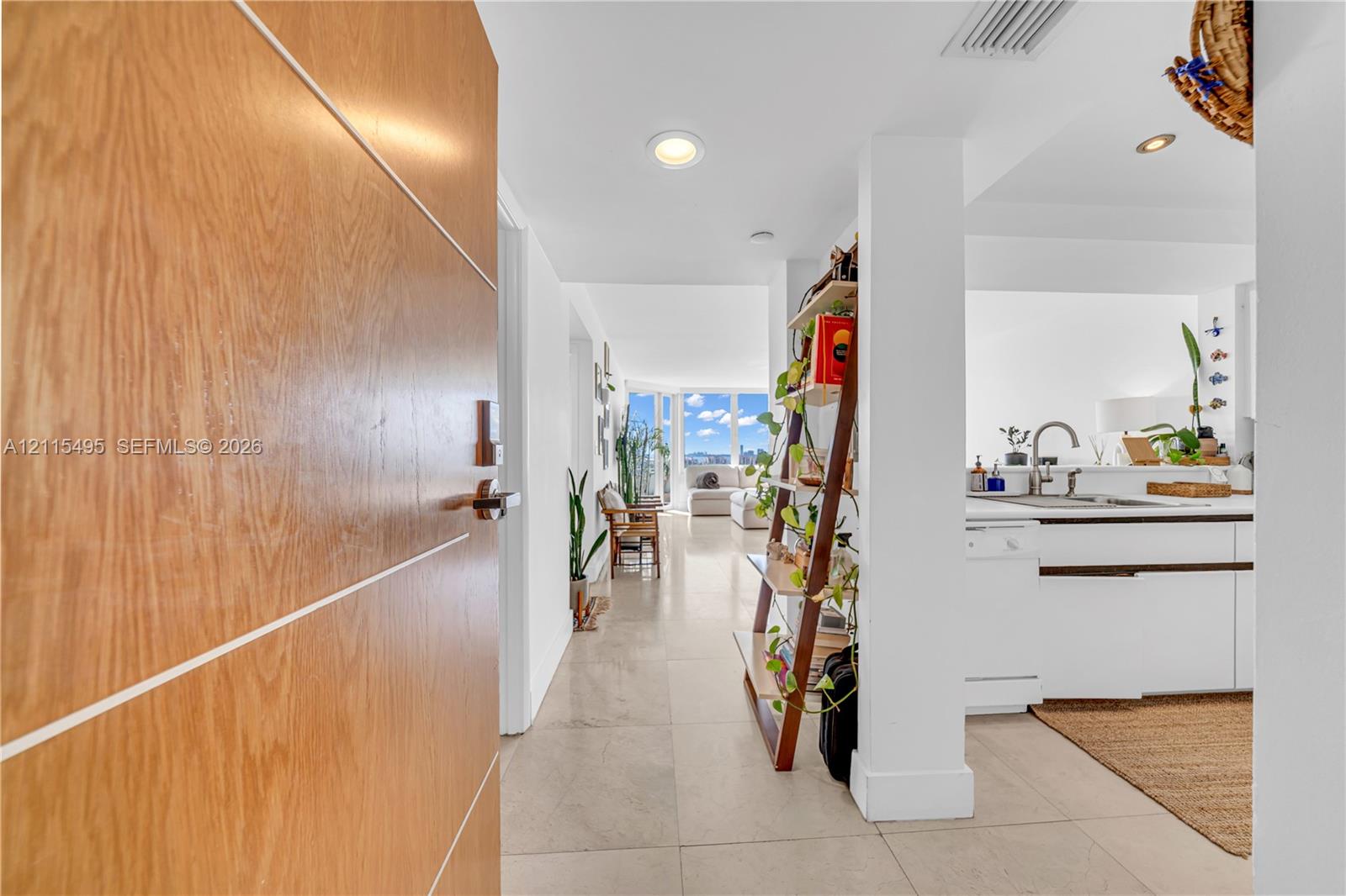 Solid wood-finish door with horizontal metal inlay, large-format tile flooring, and recessed ceiling lighting
