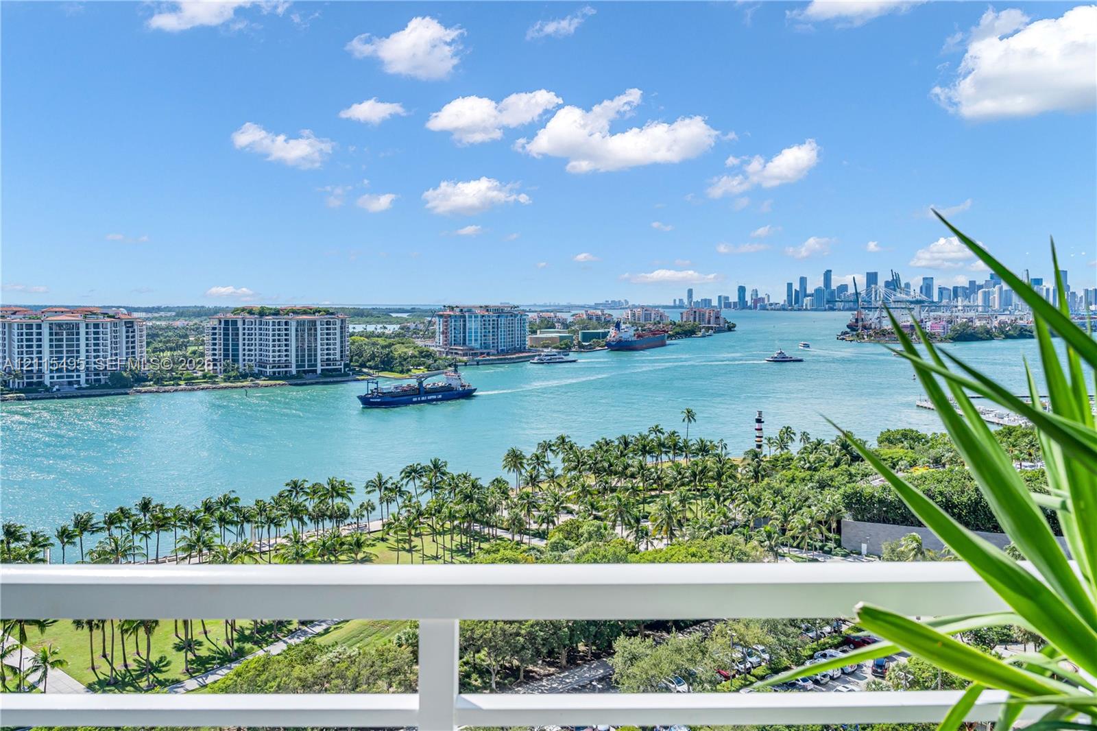 Elevated balcony featuring a white metal railing, overlooking the waterway, coastal greenery, and city skyline