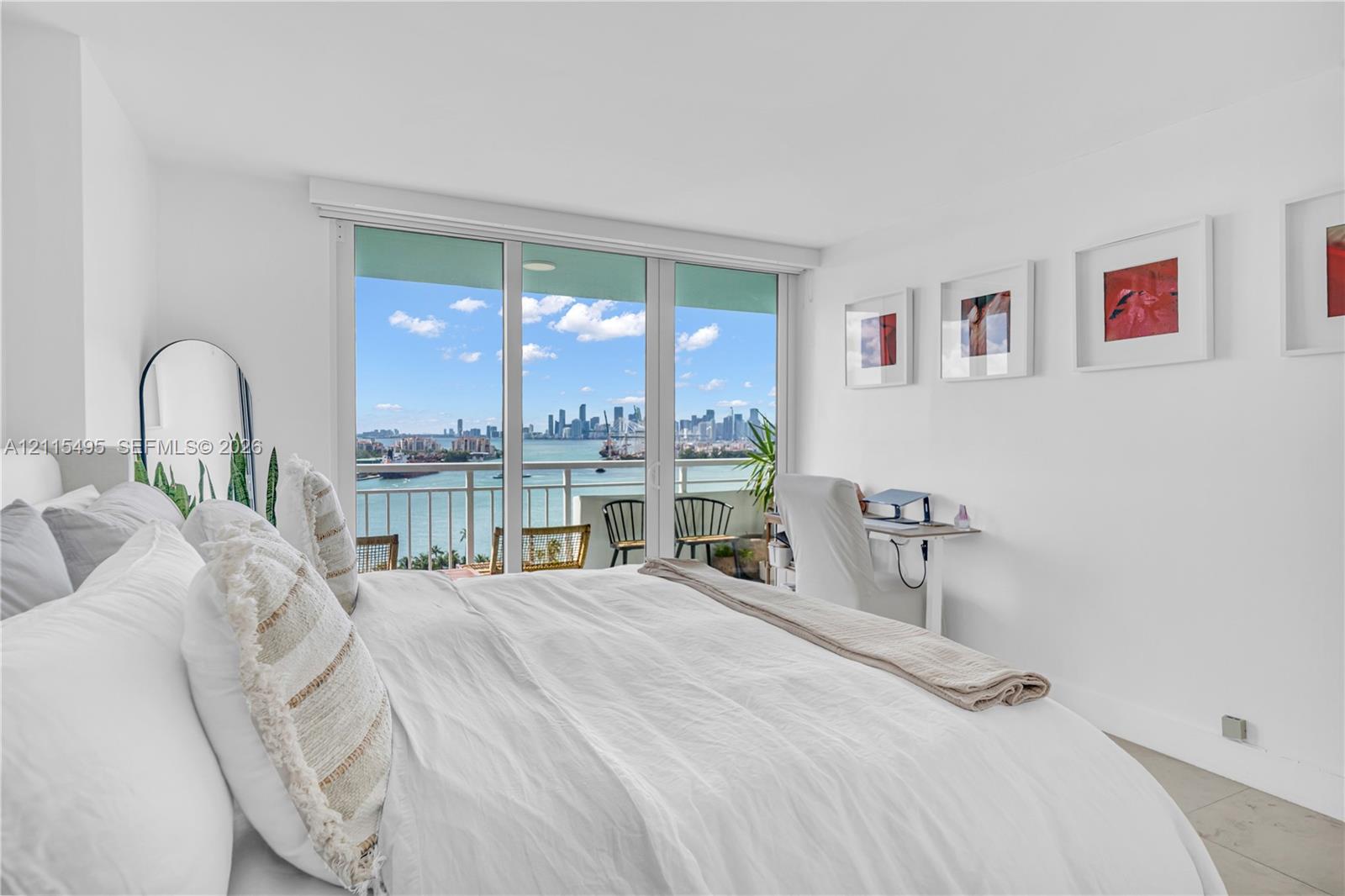 Floor-to-ceiling glass sliding doors opening to an exterior balcony with metal railing, tile flooring, and urban waterfront scenery