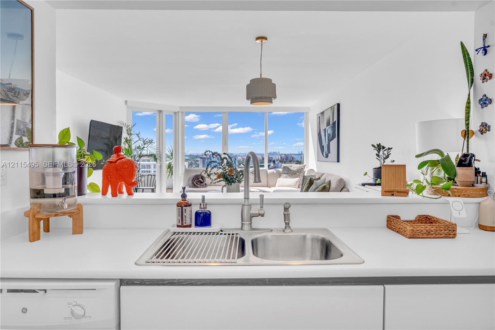 Kitchen featuring a dual-basin stainless steel sink, gooseneck faucet with sprayer, solid surface countertops, flat-panel cabinetry, and floor-to-ceiling windows