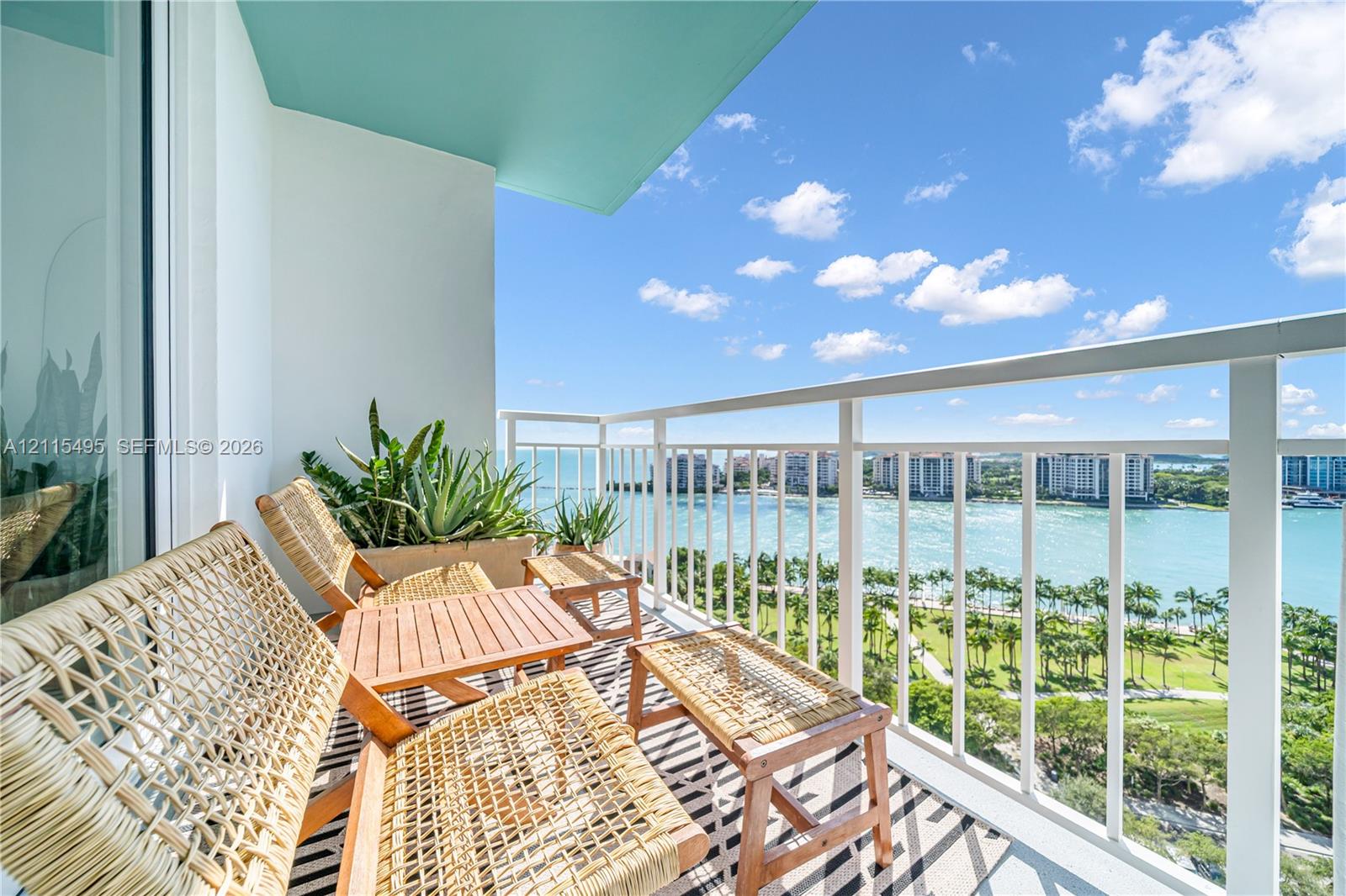 Covered balcony featuring white vertical railings, a teal ceiling finish, and expansive water and landscape surroundings