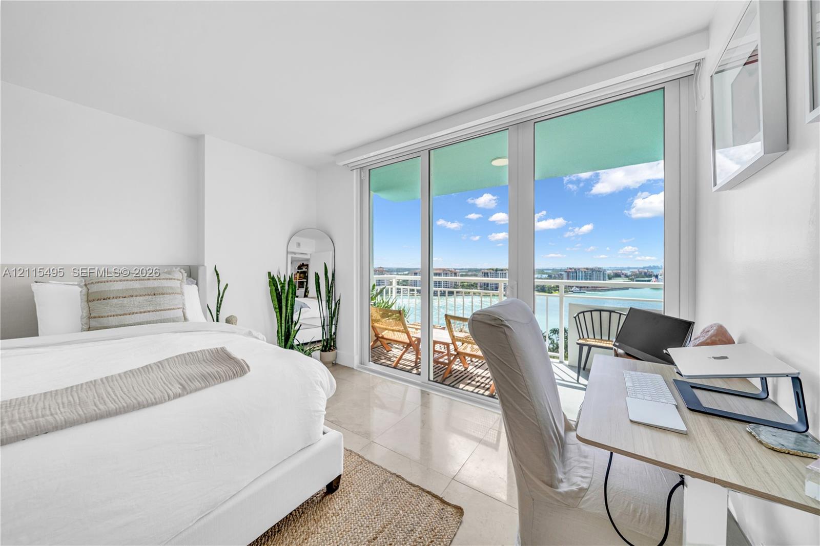 Floor-to-ceiling sliding glass doors, neutral tile flooring, and a private balcony featuring a metal railing