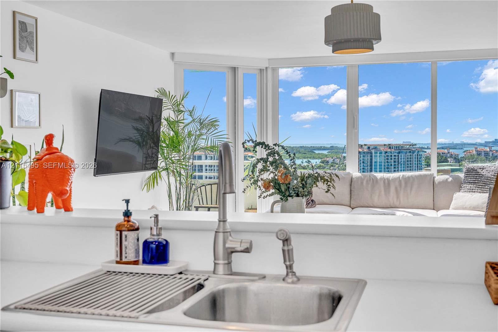 Stainless steel dual-basin undermount sink with a high-arch pull-down faucet, expansive floor-to-ceiling windows, and contemporary drum pendant lighting