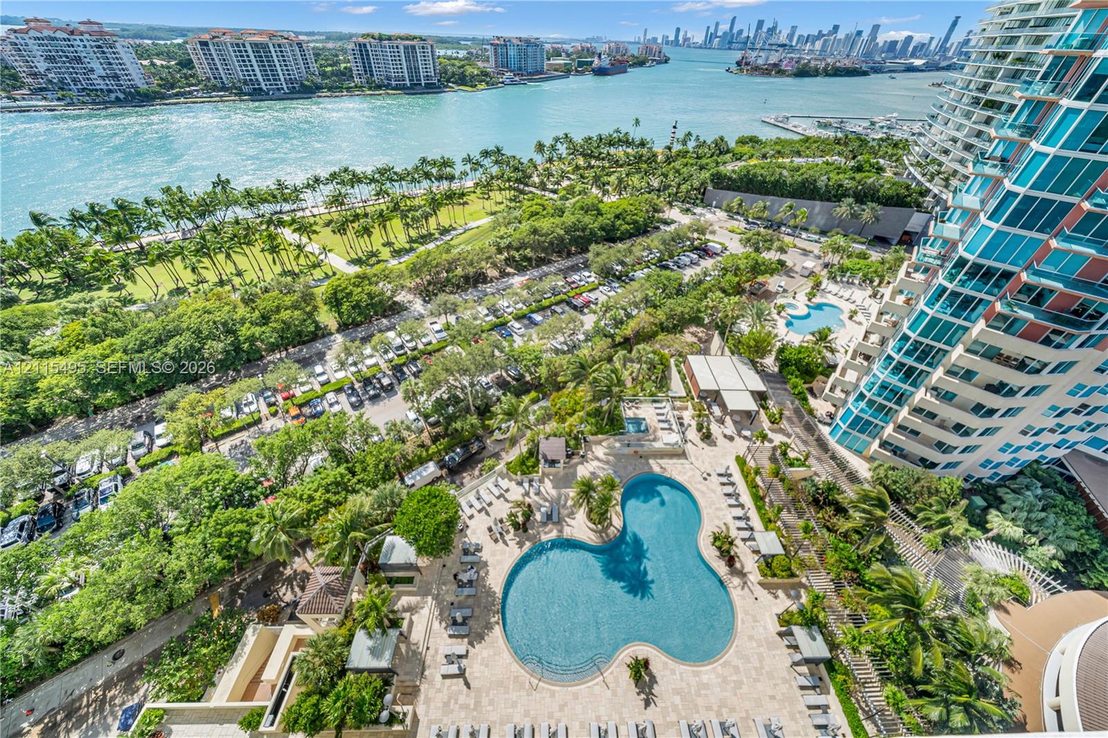 High-rise perspective featuring a curvilinear swimming pool, stone-paved deck, expansive green space, and harbor-front proximity