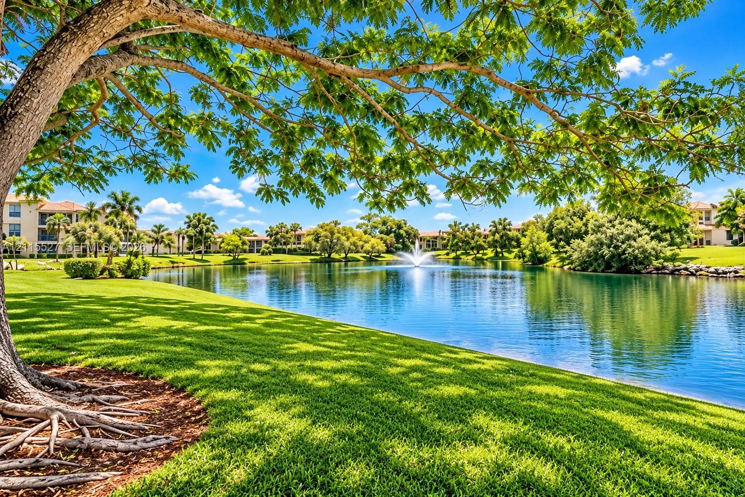 Waterfront grounds featuring a central fountain, mature canopy trees, and expansive lawn areas