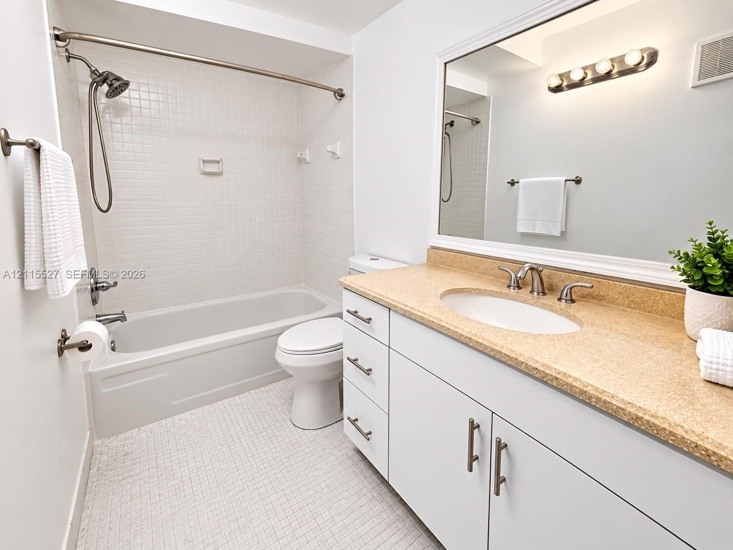 Bathroom featuring a white vanity with integrated oval sink, textured stone-finish countertop, brushed nickel hardware, and a tub-shower combination with square wall tile