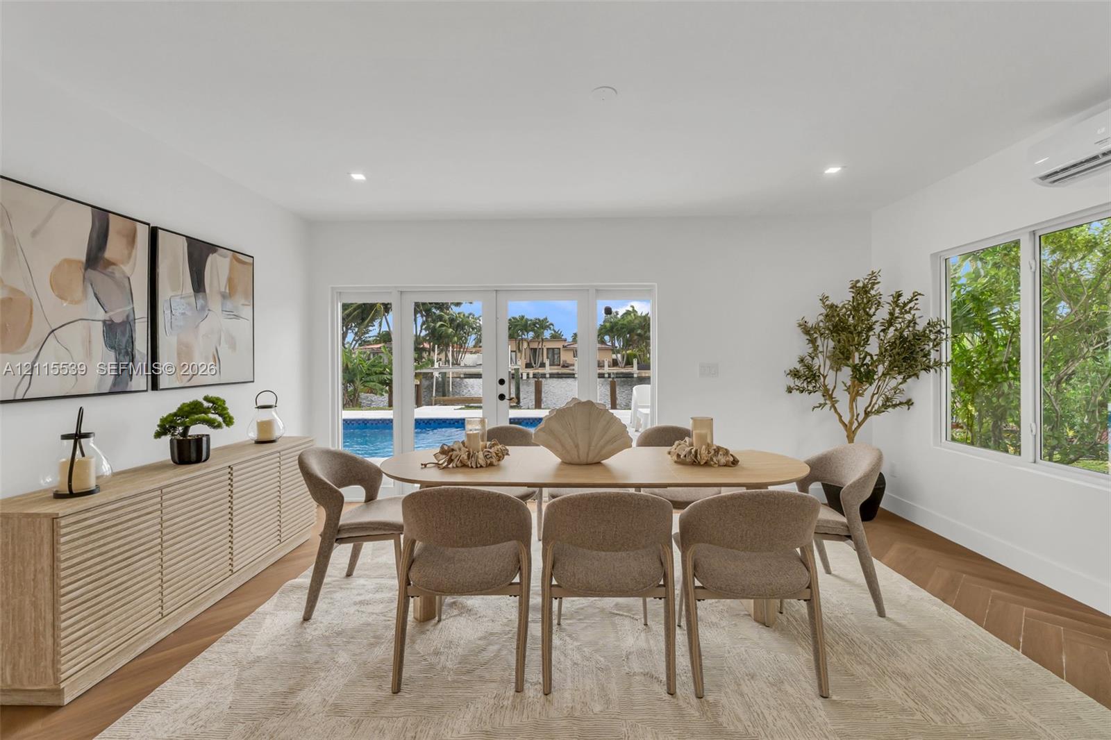 Herringbone-patterned wood-finish flooring, built-in slatted cabinetry, recessed ceiling lighting, and expansive glass paneled doors providing visibility to the pool area
