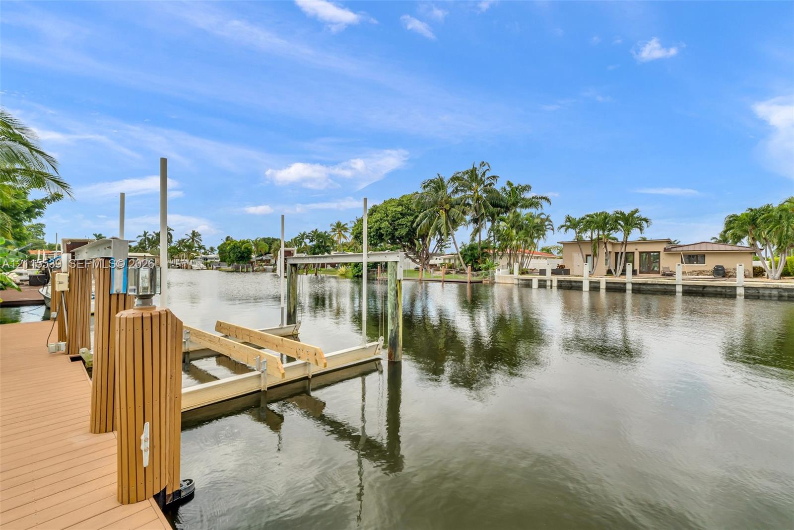 Waterfront property featuring a synthetic wood-finish dock, mechanical boat lift, and bulkhead pilings