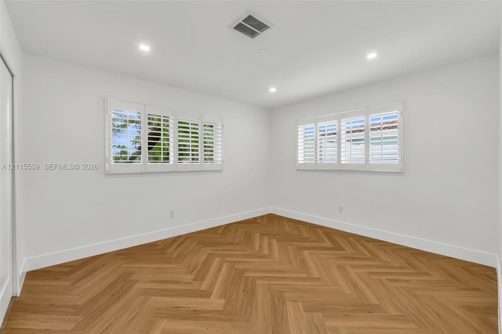 Interior room featuring wood-finish herringbone flooring, recessed lighting, and white plantation shutters