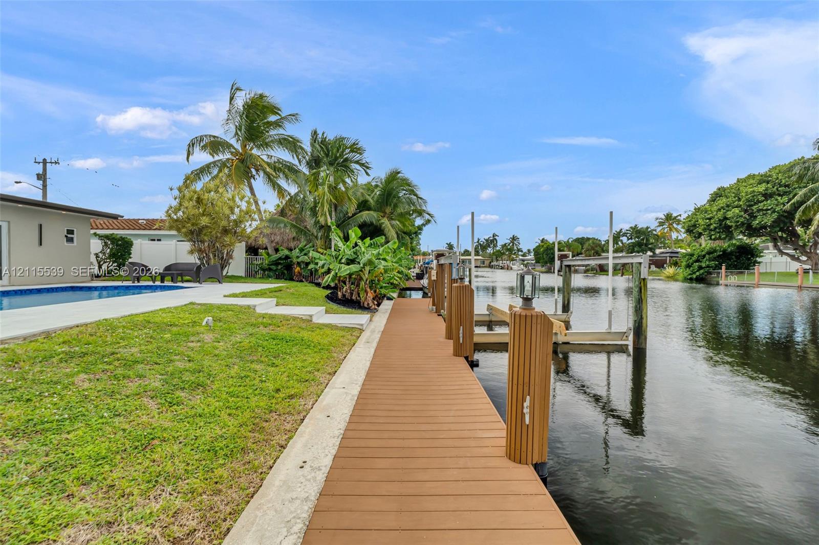 Waterfront property featuring a private dock with boat lift, composite decking, swimming pool, and concrete patio