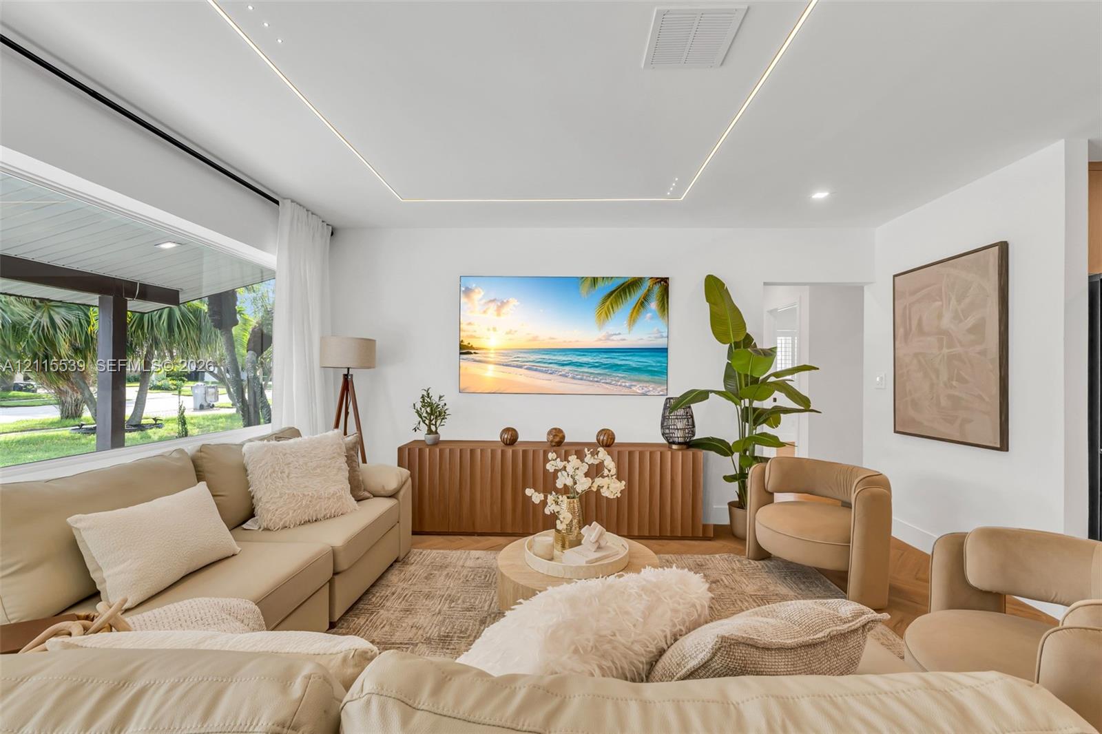 Living area featuring expansive floor-to-ceiling windows, recessed perimeter tray ceiling lighting, and herringbone-pattern wood-finish flooring